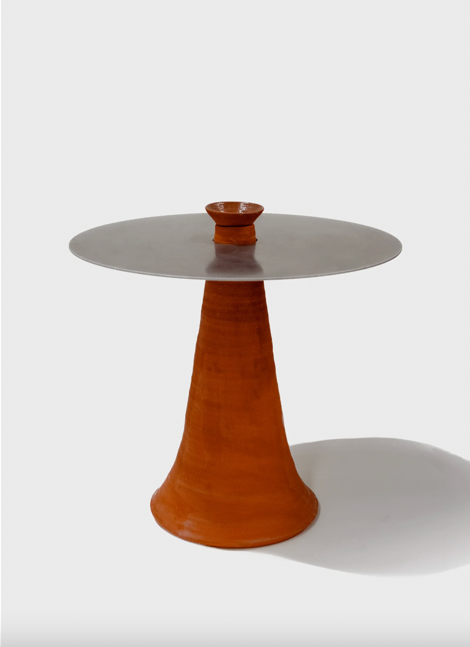 Table with a round top and conical base on a white background