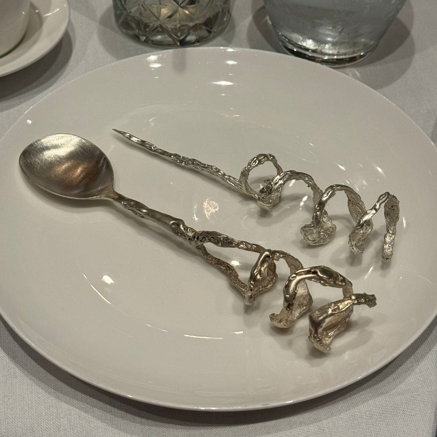 Silver cutlery worn as jewellery sitting on a plate. Designed for Perpetual Stew